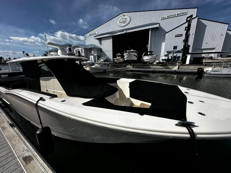 Slide: The Image of 2025 Scout 400 LXF boat docked at a marina with service hangar in background. - 33
