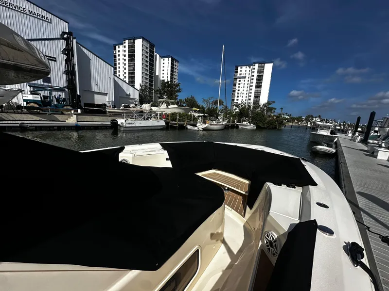 Slide: The Image of 2025 Scout 400 LXF boat docked at a marina with modern buildings in the background. - 34