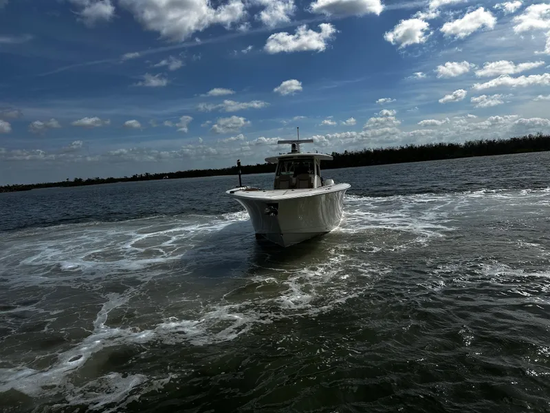 Slide: The Image of 2025 Scout 400 LXF boat cruising on a sunny day with blue skies and clouds. - 4