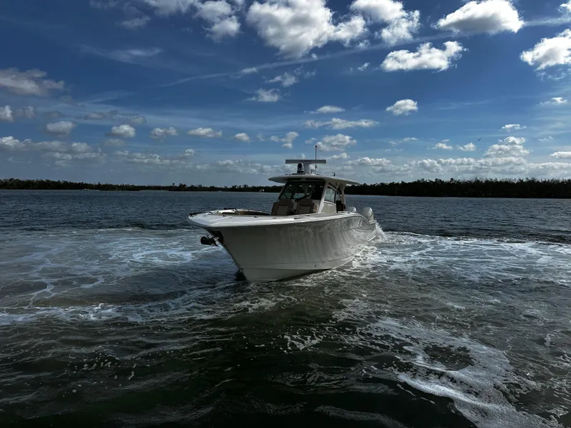 Slide: The Image of 2025 Scout 400 LXF boat cruising on open water under a partly cloudy sky. - 5