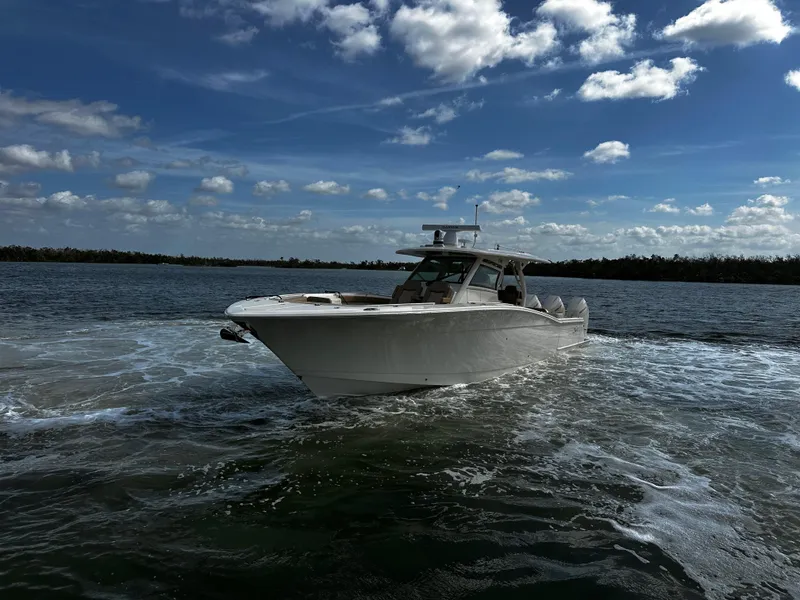 Slide: The Image of 2025 Scout 400 LXF boat cruising on open water under a partly cloudy sky. - 6