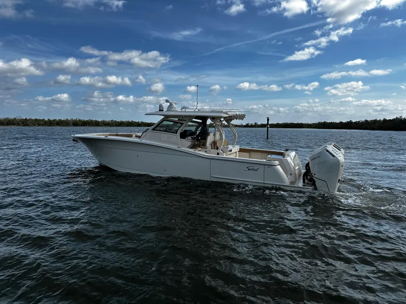 Slide: The Image of 2025 Scout 400 LXF boat cruising on open water under a partly cloudy sky. - 7