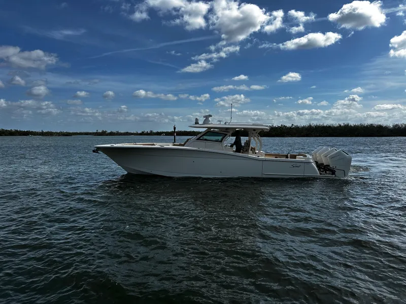 Slide: The Image of 2025 Scout 400 LXF boat cruising on a sunny day with blue skies and clouds. - 8