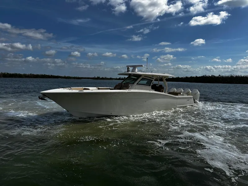 Slide: The Image of 2025 Scout 400 LXF boat cruising on a sunny day with a cloudy sky backdrop. - 9