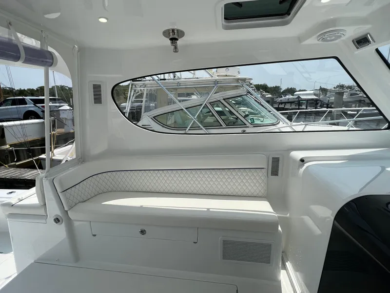 Slide: The Image of 2025 Henriques 35 Express Hardtop interior with white seating and window view of marina. - 12