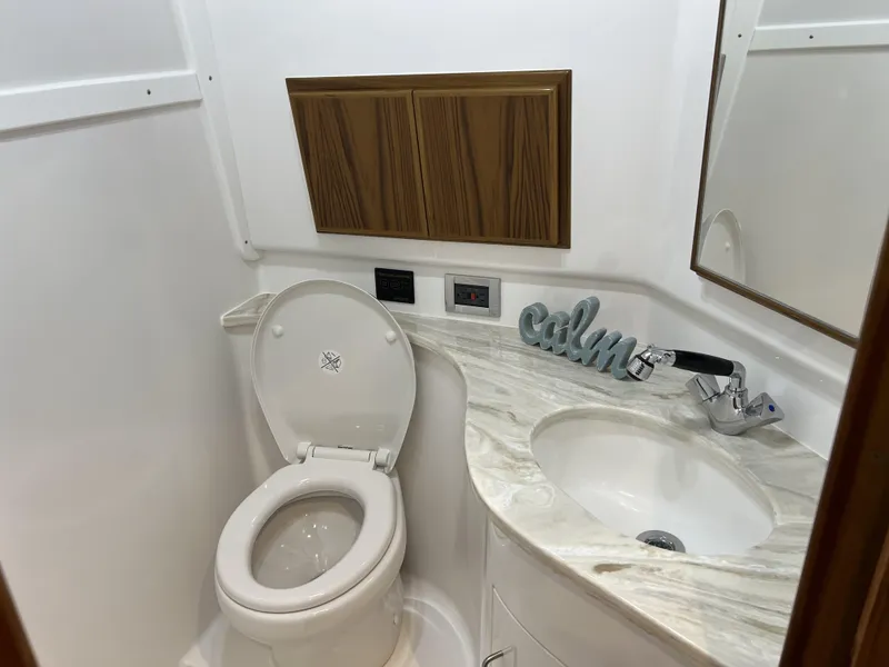Slide: The Image of 2025 Henriques 35 Express Hardtop bathroom with toilet, sink, and wooden cabinet. - 18