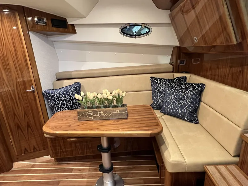 Slide: The Image of 2025 Henriques 35 Express Hardtop interior with wood finish, beige seating, and decorative pillows. - 19