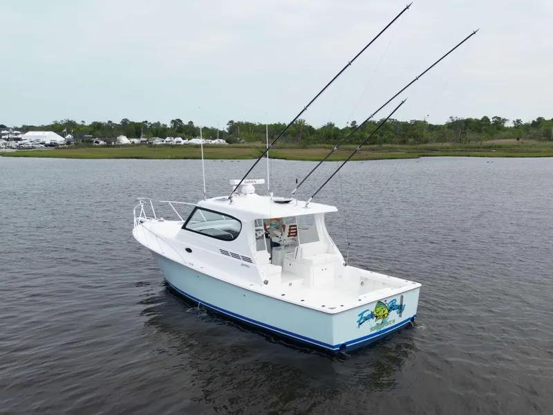 Slide: The Image of 2025 Henriques 35 Express Hardtop boat on calm water, featuring fishing rods and sleek design. - 2