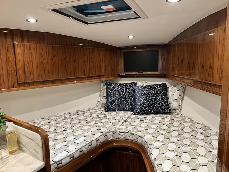 Slide: The Image of 2025 Henriques 35 Express Hardtop cabin with modern wood finish and geometric-patterned bedding. - 21