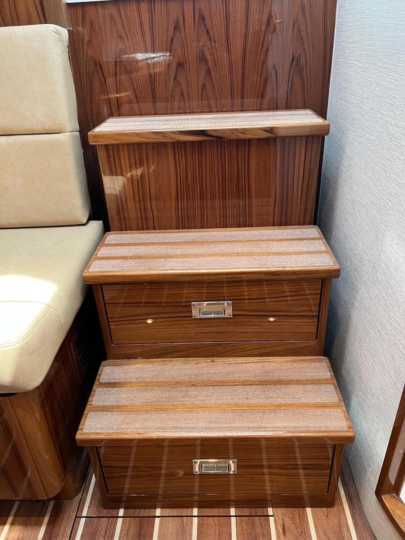 Slide: The Image of Wooden steps with storage on a 2025 Henriques 35 Express Hardtop boat interior. - 24