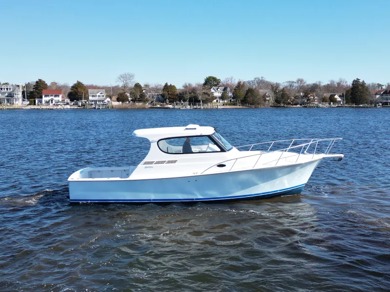 Slide: The Image of 2025 Henriques 35 Express Hardtop boat on calm water, with shoreline in background. - 3