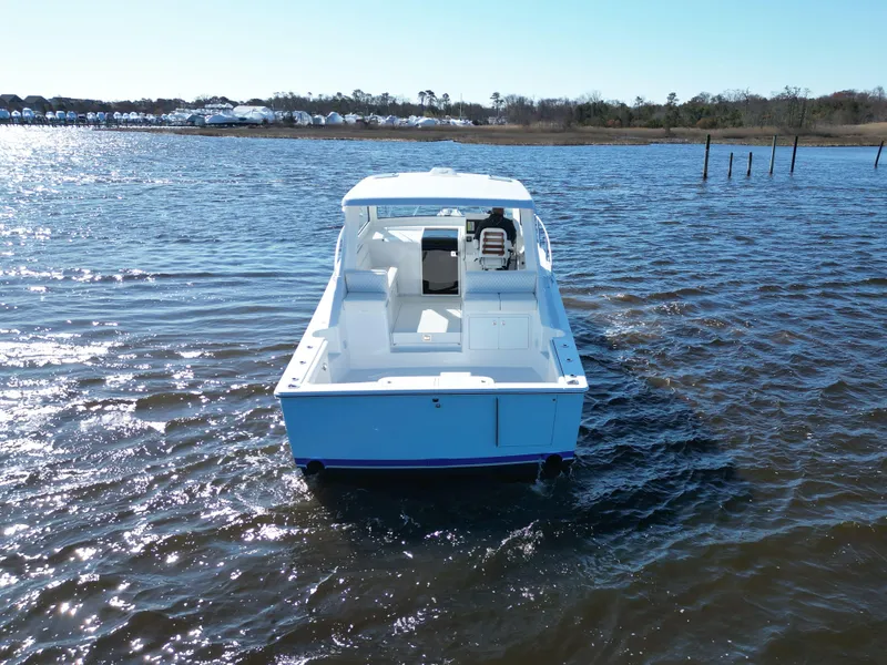 Slide: The Image of 2025 Henriques 35 Express Hardtop boat on calm water, rear view. - 5