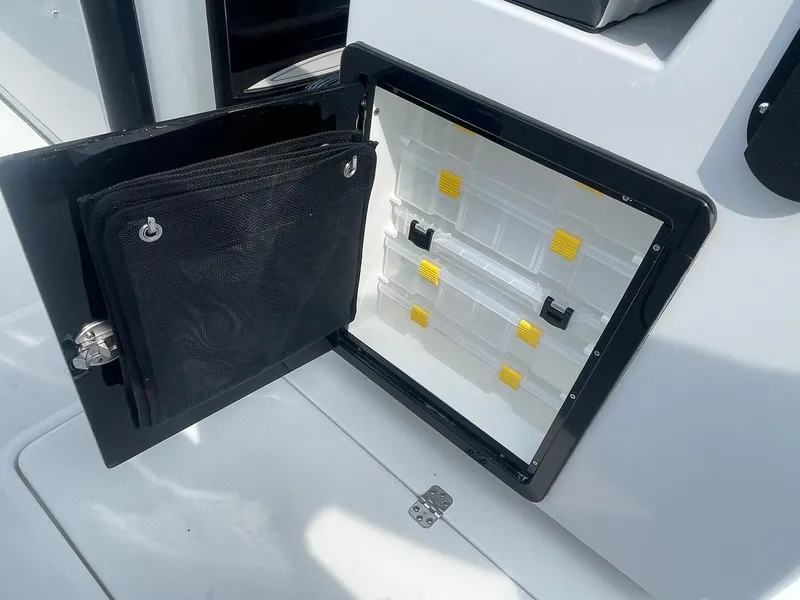 Slide: The Image of 2025 Sea Pro 262 Offshore storage compartment with organized tackle boxes and mesh pouch. - 63