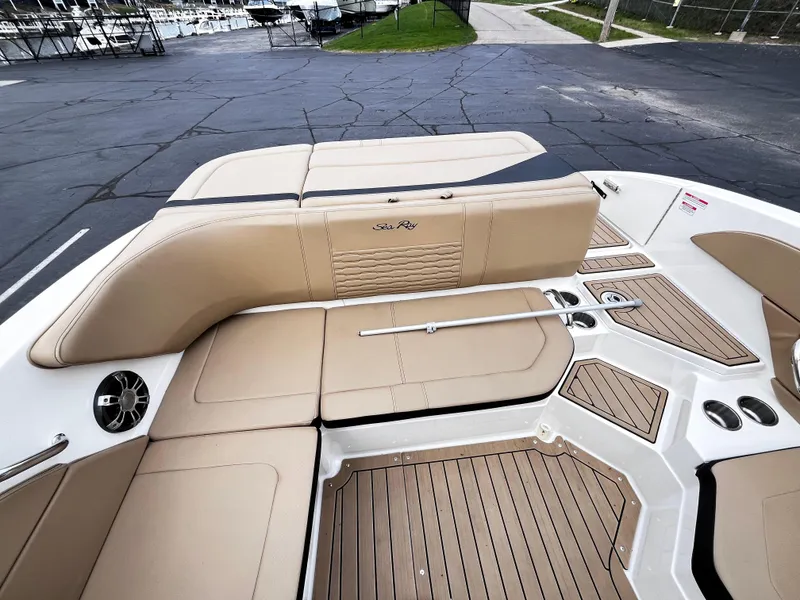 Slide: The Image of 2022 Sea Ray SPX 210 boat interior with tan seating and wood-style flooring. - 2