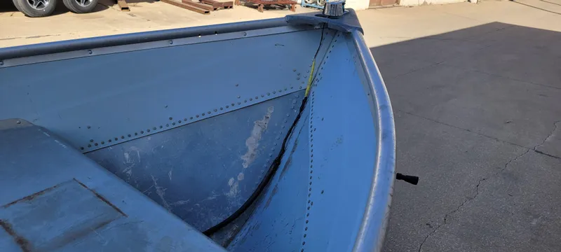 Slide: The Image of 1988 Lowe 14' V boat, blue exterior, docked on concrete surface. - 15