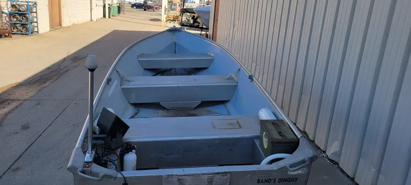 Slide: The Image of 1988 Lowe 14' V boat parked in an alleyway, featuring basic equipment and seating. - 4