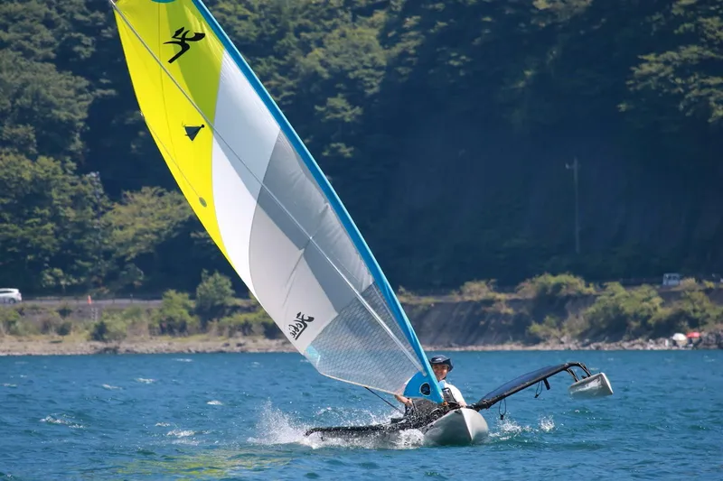 Slide: The Image of Sailing Hobie Mirage Tandem Island 2012 on a scenic lake with lush forest backdrop. - 2
