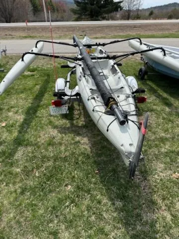 Slide: The Image of 2012 Hobie Mirage Tandem Island kayak on grass, featuring outriggers and trailer. - 4