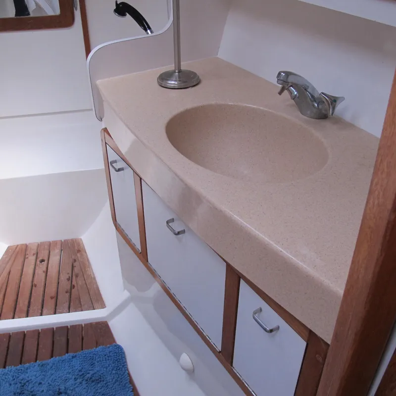 Slide: The Image of Bathroom sink area in a 1997 Catalina 42 MkII yacht, featuring wood accents and storage cabinets. - 38