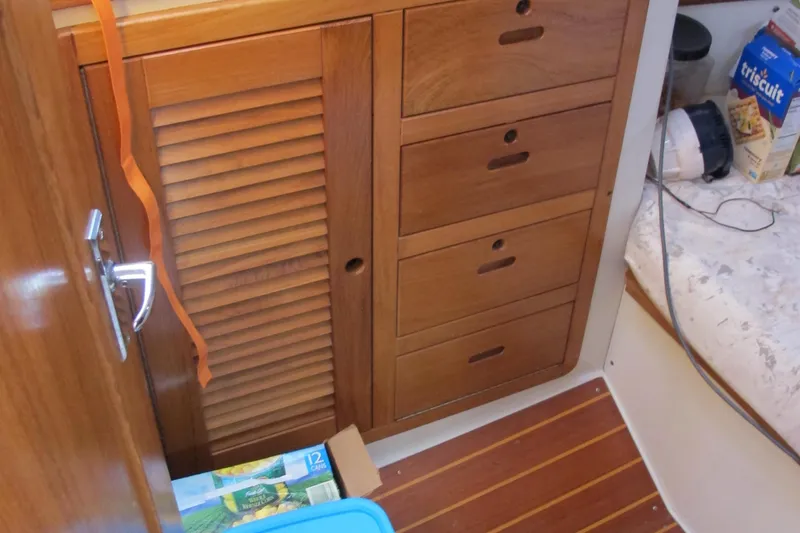 Slide: The Image of Wooden cabinetry inside a 1997 Catalina 42 MkII sailboat, featuring drawers and a louvered door. - 45