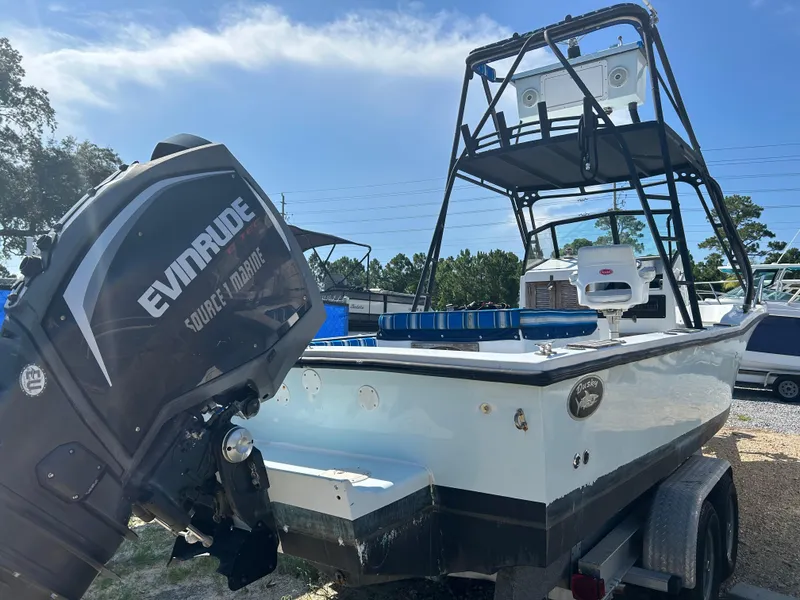 Slide: The Image of 1992 Dusky 256 boat with Evinrude motor, parked on a trailer under clear skies. - 1