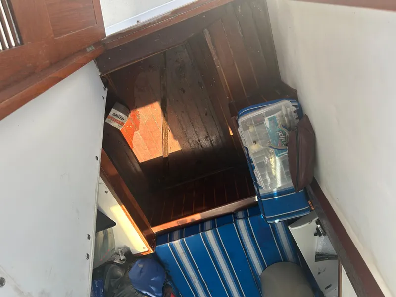 Slide: The Image of Interior cabin of a 1992 Dusky 256 boat with wooden flooring and striped seating. - 10