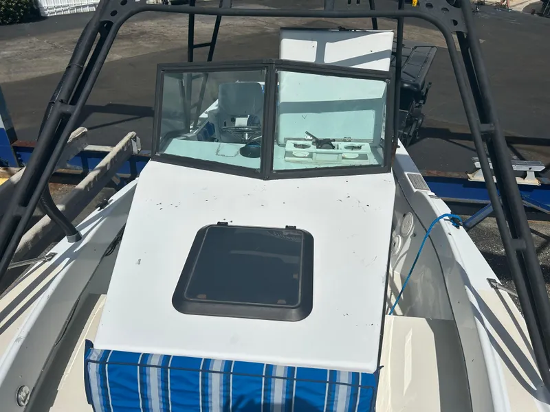 Slide: The Image of 1992 Dusky 256 boat with blue-striped seating and windshield, docked on a trailer. - 13