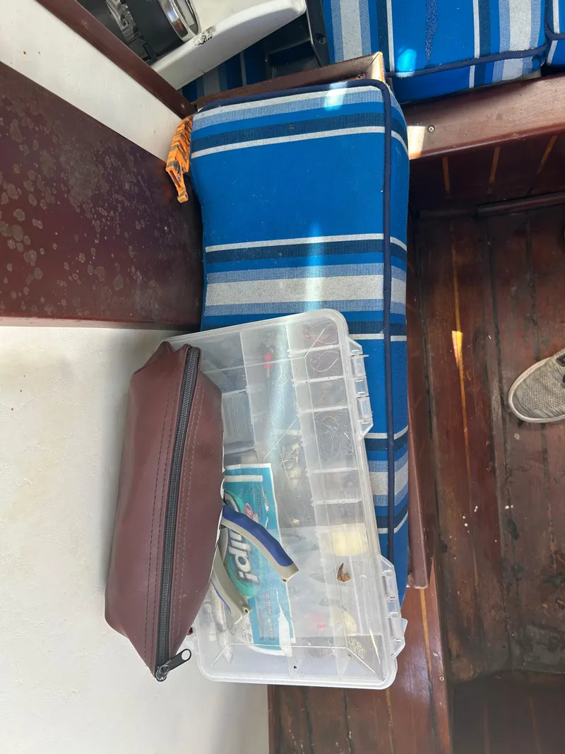 Slide: The Image of Fishing tackle box and pouch on a 1992 Dusky 256 boat with blue-striped seating. - 8