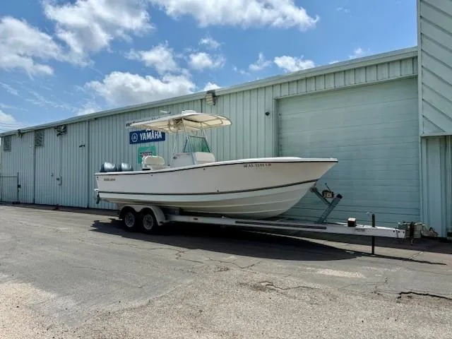 Slide: The Image of 2001 Regulator 26 Forward Seating boat on trailer, parked near a Yamaha service building. - 2