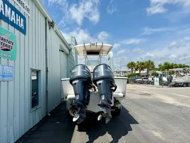 Slide: The Image of 2001 Regulator 26 Forward Seating boat with twin outboard motors, parked beside a building. - 3