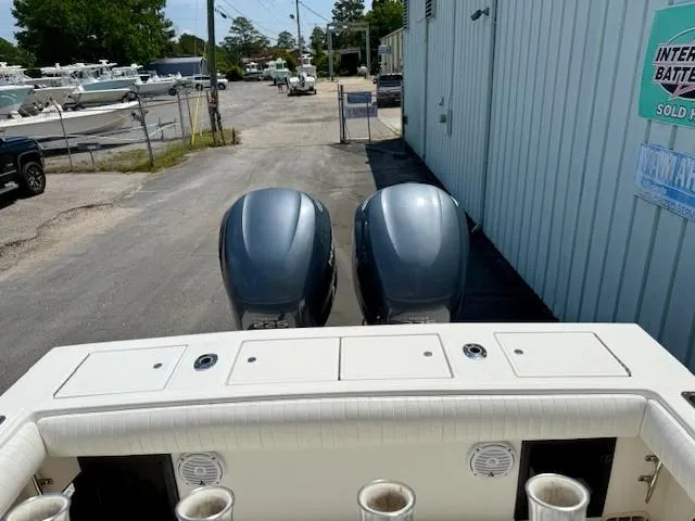 Slide: The Image of 2001 Regulator 26 Forward Seating boat with dual outboard motors, parked near a marina. - 4