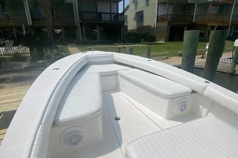 Slide: The Image of 2001 Regulator 26 Forward Seating boat with white cushioned seats, docked near waterfront homes. - 8