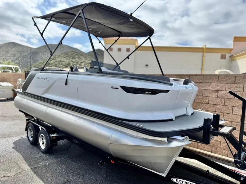 Slide: The Image of 2025 Manitou Cruise 20 Bench Twin Tube pontoon boat on trailer, with canopy, outdoors. - 1