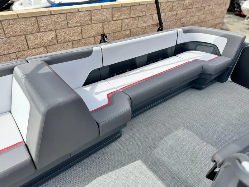 Slide: The Image of 2025 Manitou Cruise 20 Bench Twin Tube boat interior with sleek gray seating and red accents. - 11