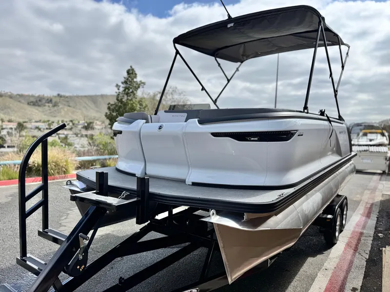 Slide: The Image of 2025 Manitou Cruise 20 Bench Twin Tube pontoon boat on trailer, outdoor setting. - 4