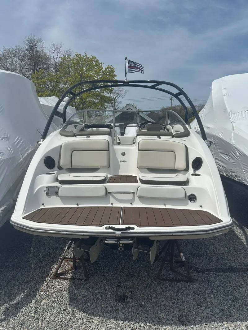 Slide: The Image of 2013 Yamaha Boats 242 Limited S, rear view, docked, with American flag in background. - 3