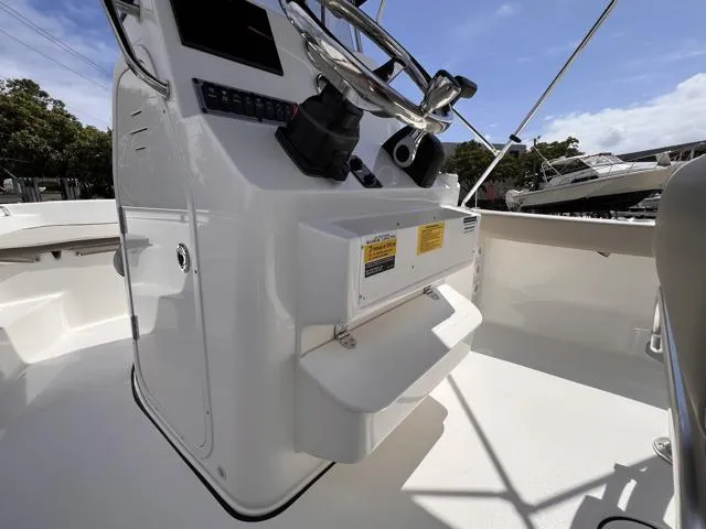 Slide: The Image of 2025 Key West 189 FS boat console with steering wheel and controls, docked under clear sky. - 13