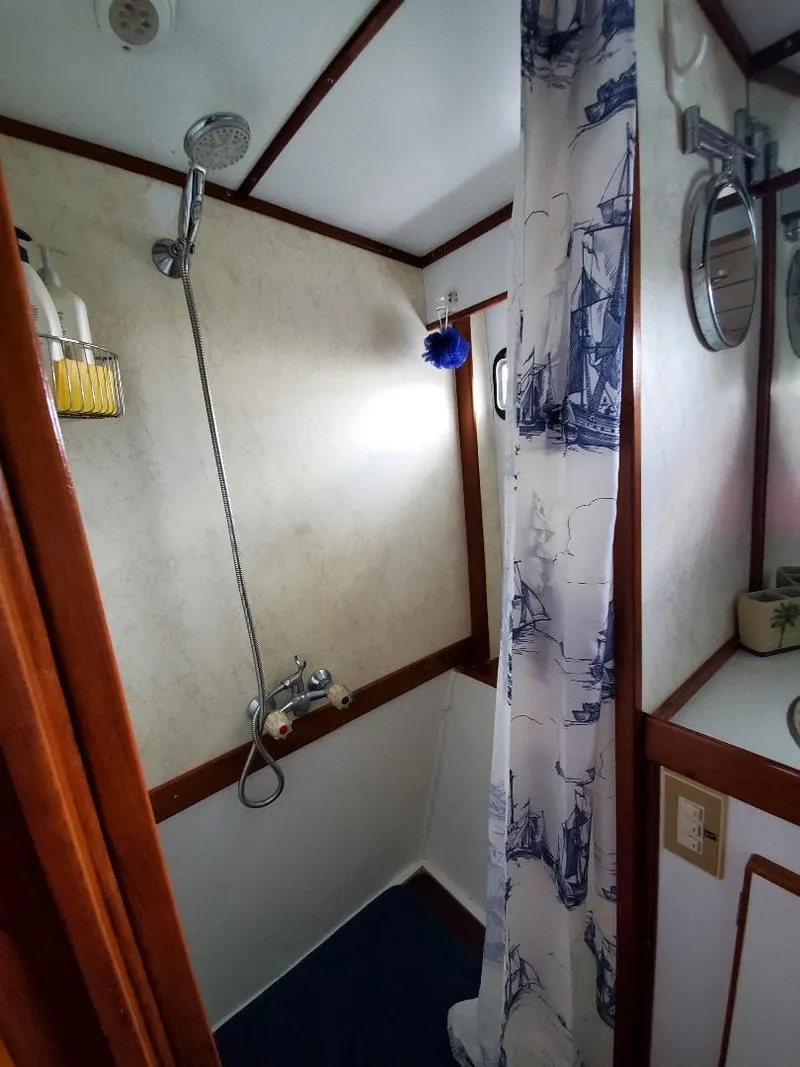 Slide: The Image of 1987 Tayana 45 Expedition Trawler bathroom with shower, nautical-themed curtain, and wooden accents. - 19