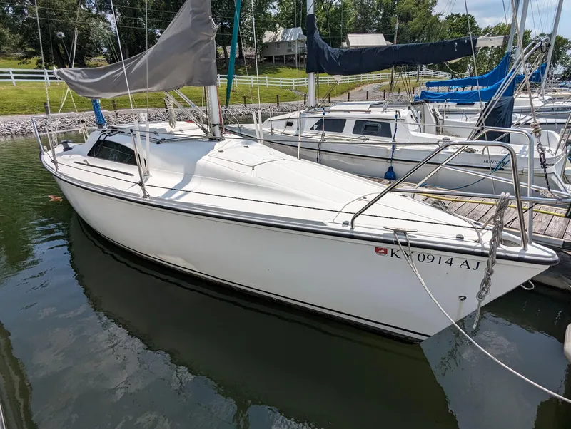 Slide: The Image of 1987 Hunter 26.5 sailboat docked in a marina, surrounded by other boats. - 0
