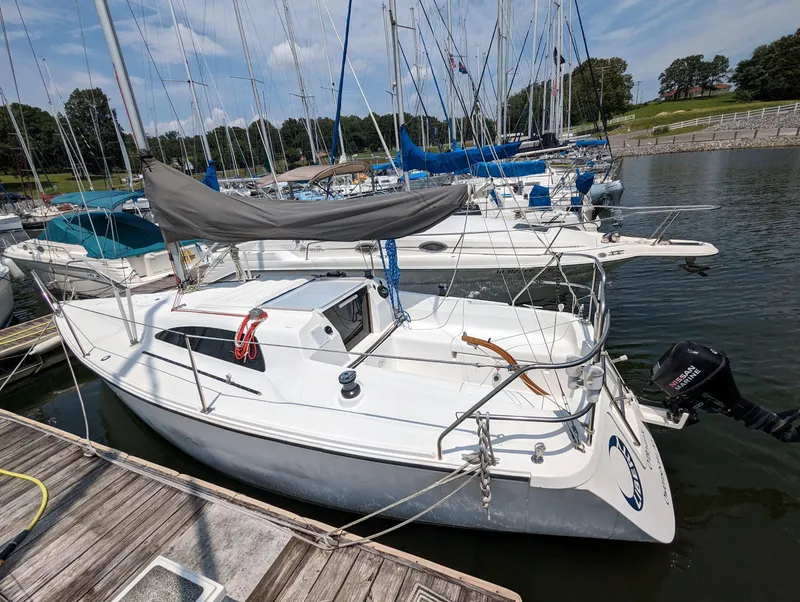 Slide: The Image of 1987 Hunter 26.5 sailboat docked at marina, featuring sleek design and outboard motor. - 1