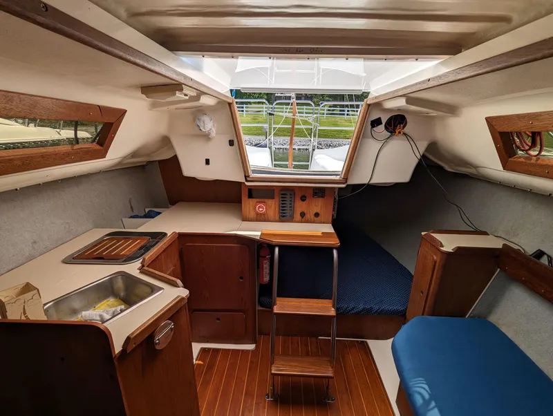 Slide: The Image of Interior of a 1987 Hunter 26.5 sailboat, featuring a compact kitchen and cozy seating area. - 5