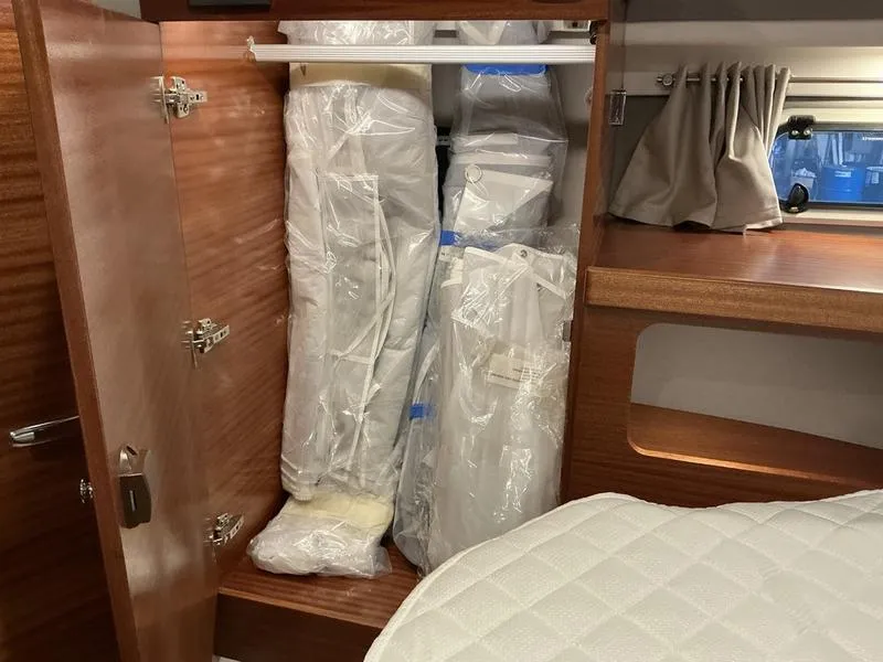 Slide: The Image of Storage area in a 2025 Nimbus 365 Coupe boat with packaged items and wooden finish. - 30