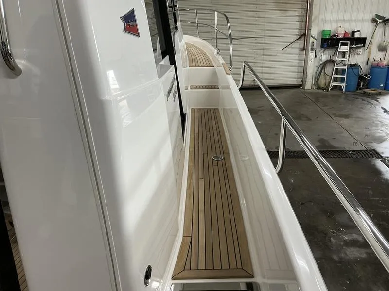 Slide: The Image of 2025 Nimbus 365 Coupe yacht with sleek wooden deck in a garage setting. - 8