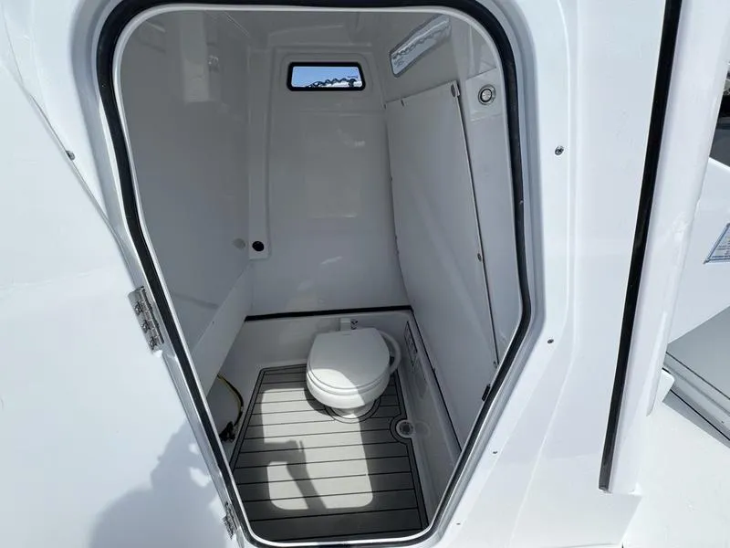 Slide: The Image of 2025 Sportsman Masters 267 boat interior with compact marine toilet and window. - 12