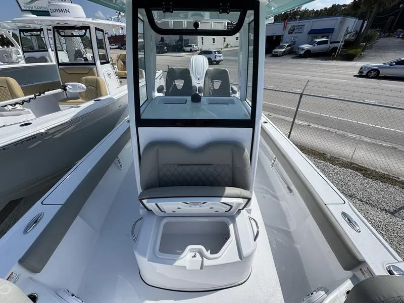 Slide: The Image of 2025 Sportsman Masters 267 boat interior with seating and storage, docked near a road. - 13