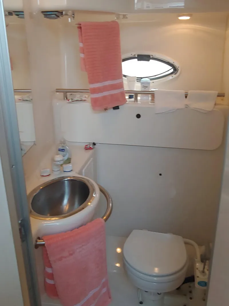 Slide: The Image of Compact bathroom in 2000 Maxim Yachts 3300SCR, featuring sink, toilet, and porthole window. - 3