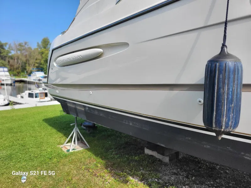Slide: The Image of Maxim Yachts 3300SCR 2000 model on land with blue fender, grassy background. - 8