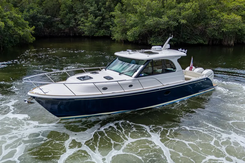 Slide: The Image of 2021 Hinckley Sport Boat 40 X cruising in a lush, green waterway. - 2