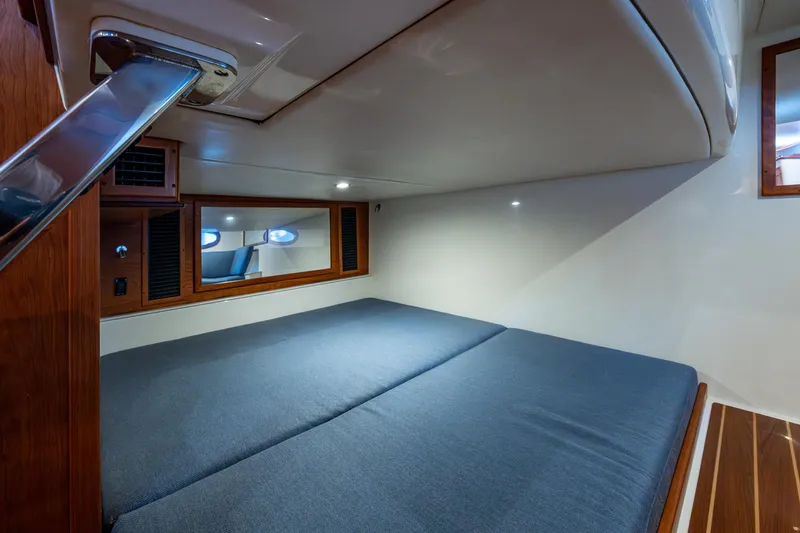 Slide: The Image of 2021 Hinckley Sport Boat 40 X cabin interior with cozy bed and wooden accents. - 22