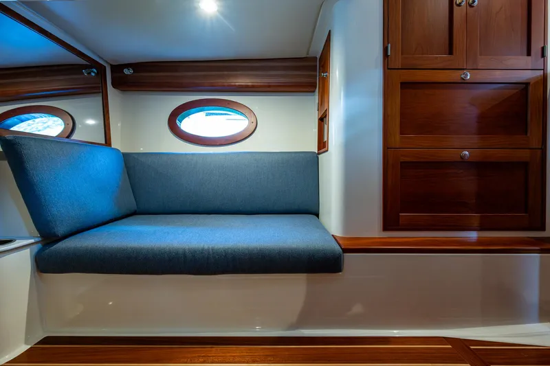 Slide: The Image of 2021 Hinckley Sport Boat 40 X interior with blue seating and wooden cabinetry. - 24